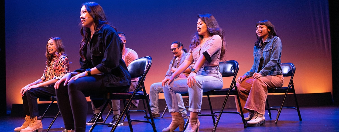 Actresses sit on chairs on a stage